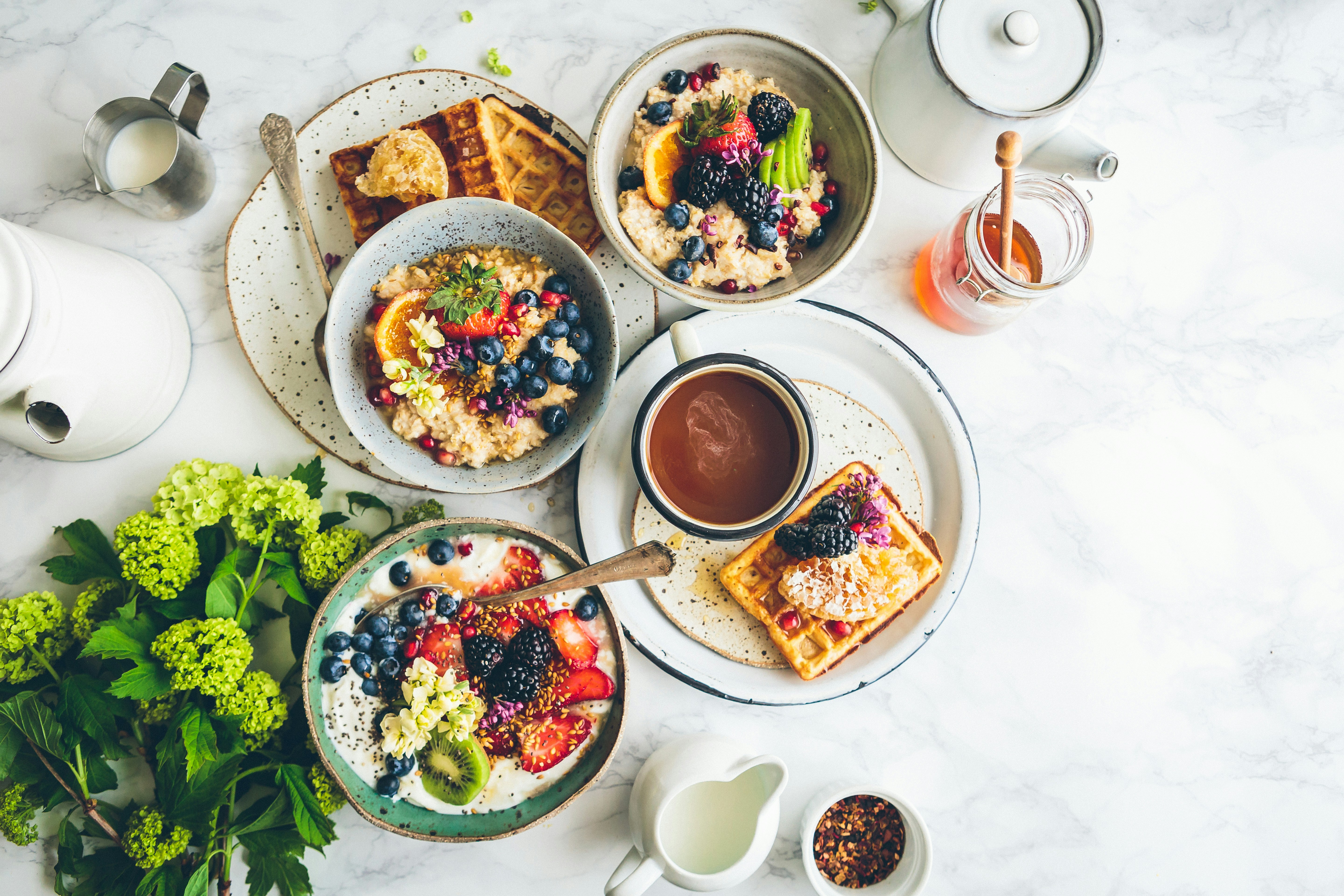 Healthy breakfast setup with colorful fruits, oats, and nutritious ingredients arranged on a wooden table