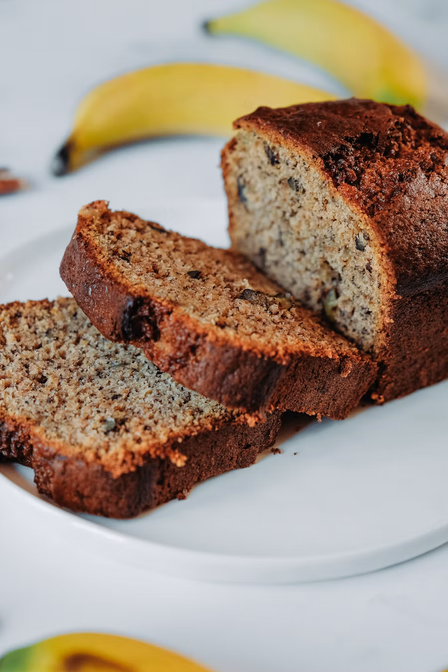 High-protein banana bread sliced on cutting board, showing moist golden interior with visible banana pieces and nuts